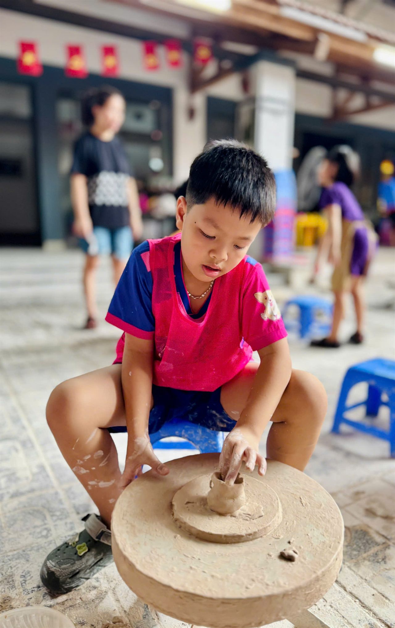 Bé trai tạo hình chiếc cốc trên bàn xoay gốm